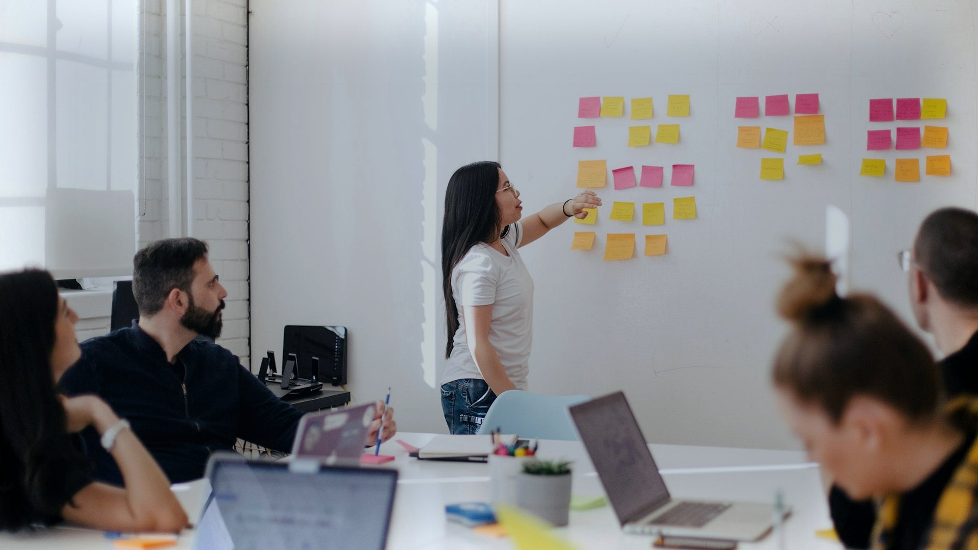 Facilitator working with a group around a table and sticky notes on the wall